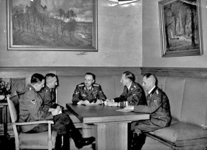 ADN-ZB-Archiv Der Reichsführer SS Heinrich Himmler bespricht  [in München] mit dem Chef der Sicherheitspolizei Reinhard Heydrich und dessen Mitarbeitern des bisherige Ermittlungsergebnis über den Bombenanschlag im Bürgerbräukeller in München am 8.11.1939 und legt die Grundlinien für die weitere Bearbeitung fest. UBz: v.l.n.r.: SS-Obersturmbannführer Huber, SS-Oberführer [Arthur] Nebe, Reichsführer-SS Heinrich Himmler, SS-Gruppenführer Reinhard Heydrich und SS-Oberführer [Heinrich] Müller 27.11.1939 [Herausgabedatum]